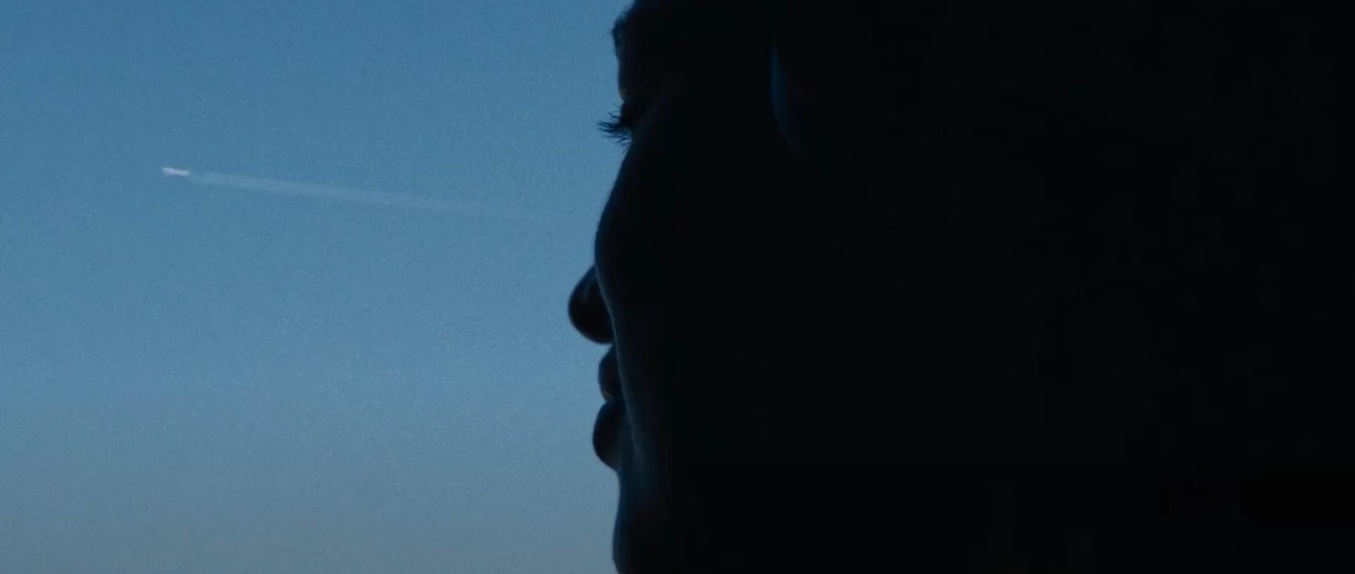 Picture of a face looking at a plane in the sky